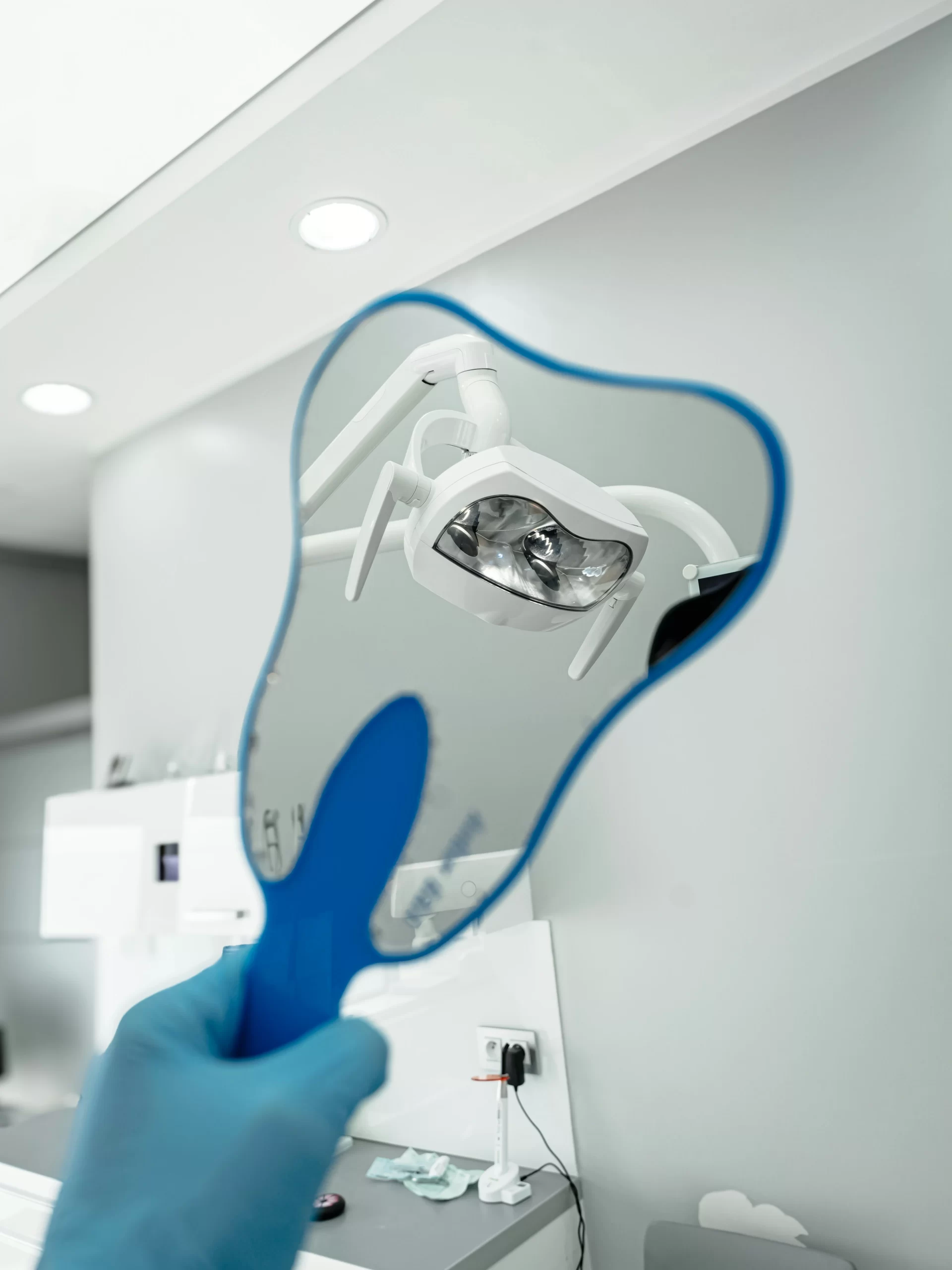 First Dental Cleaning at GPD: Step-by-Step Guide – Reflection of a dental clinic light in a mirror during a routine teeth cleaning procedure.