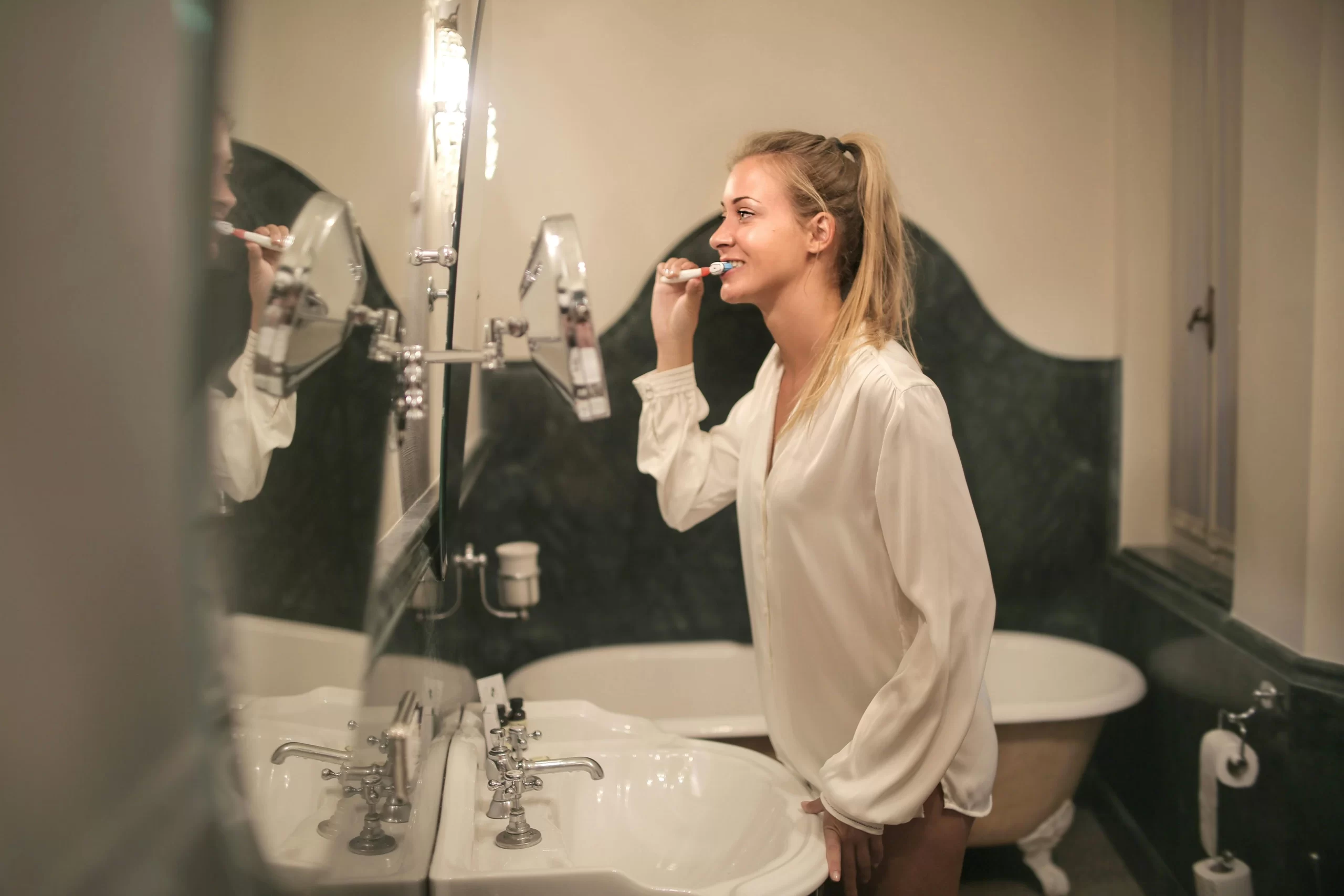 A woman brushing her teeth for tooth sensitivity.