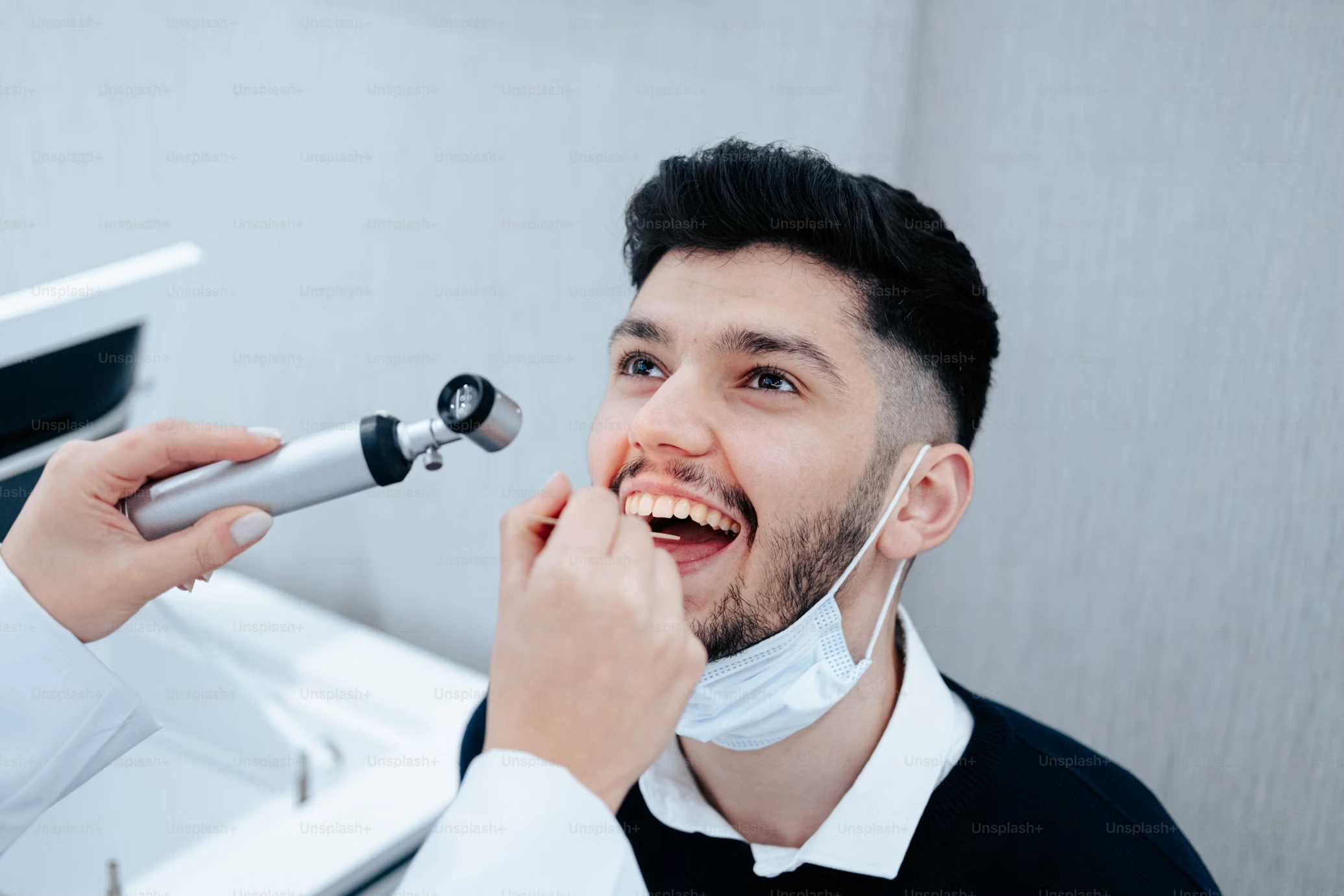 A male patient being examined by a dentist using dental tools before the dental cleaning.