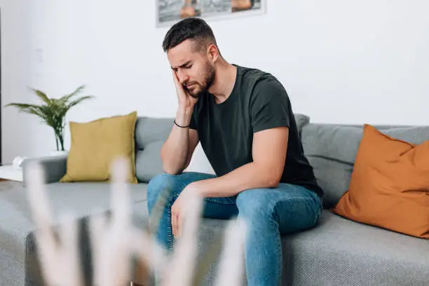 person with tooth pain holding jaw